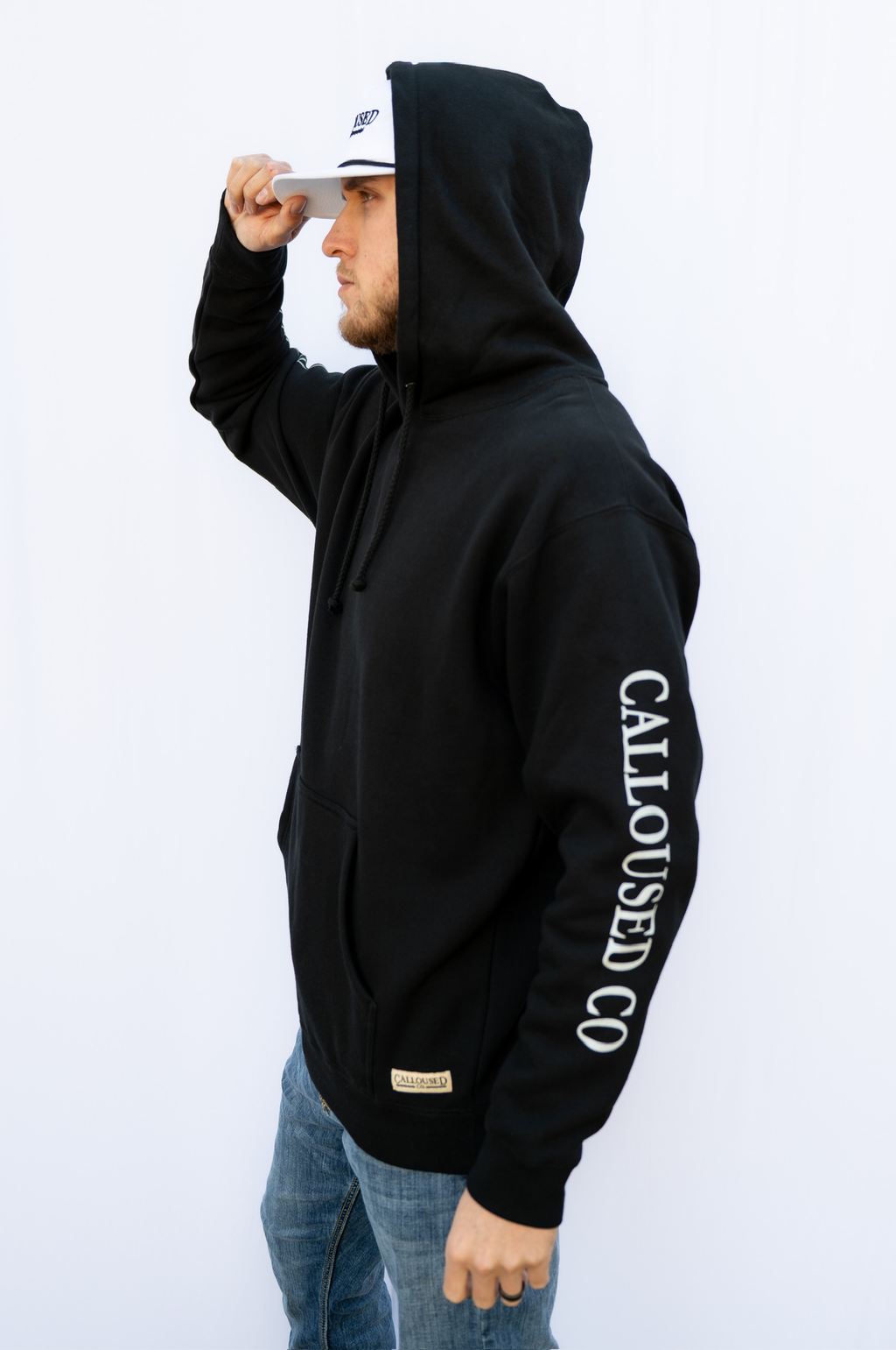 Man wearing a black heavyweight hoodie with 'Calloused Co' branding on a white background