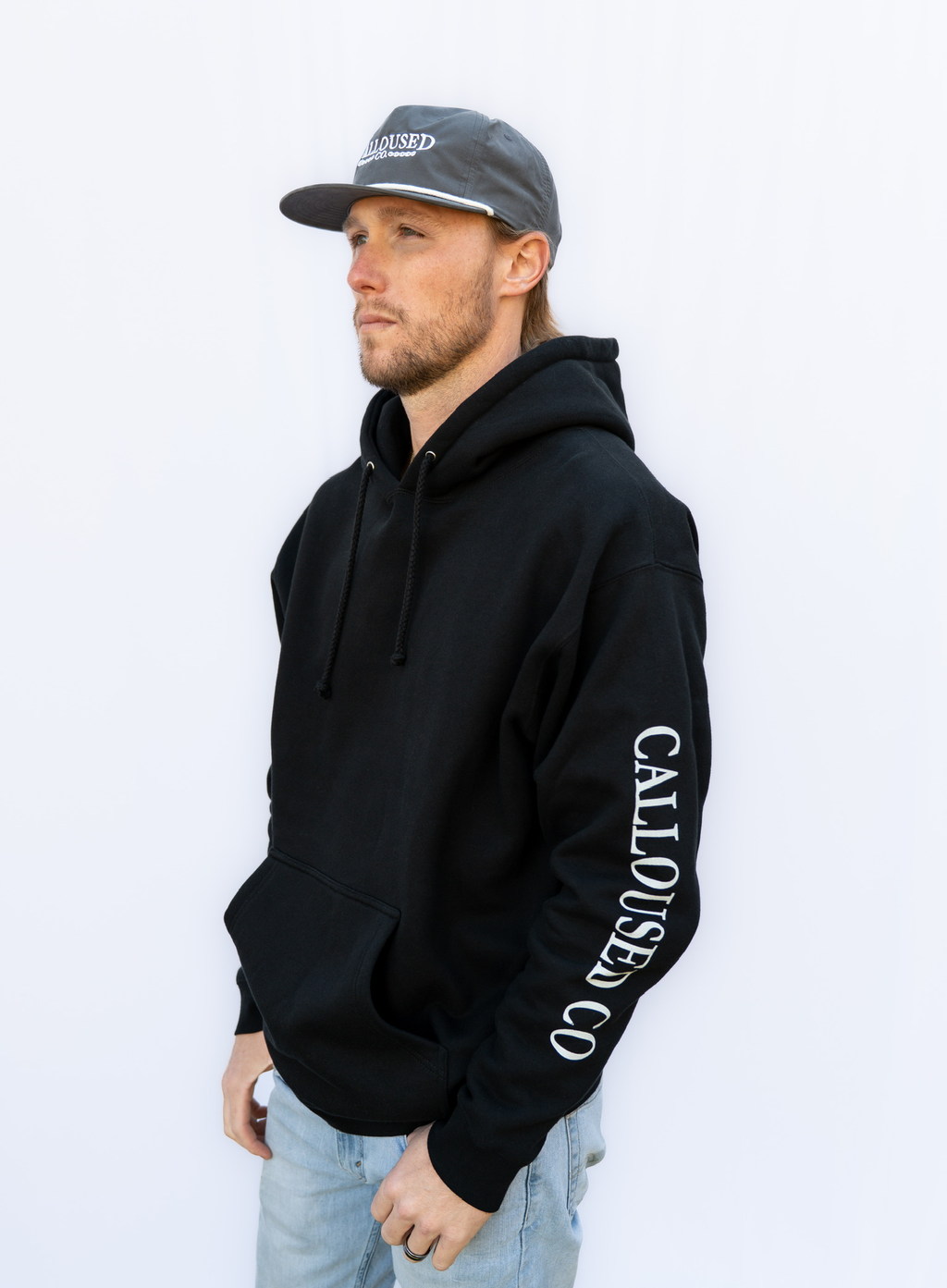 Man wearing a black hoodie with 'Calloused Co' branding on a white background