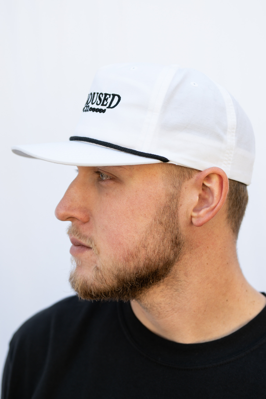 Man wearing a white cap with 'Calloused Co' logo on a plain background