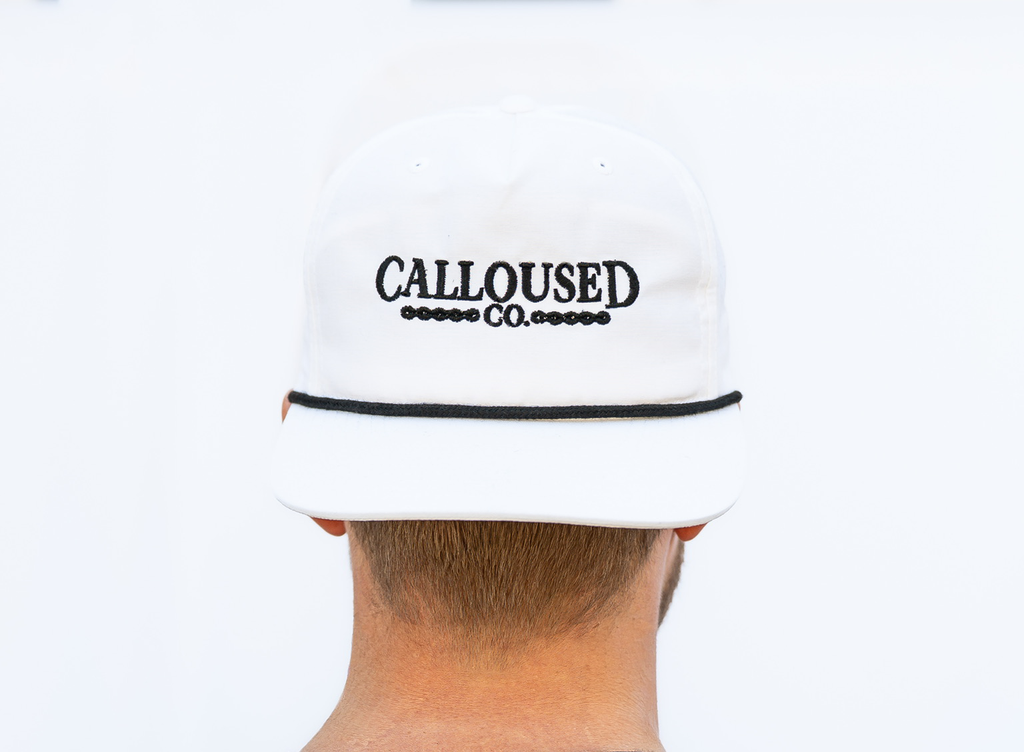 White cap with 'Calloused Co.' logo worn by a person on a white background