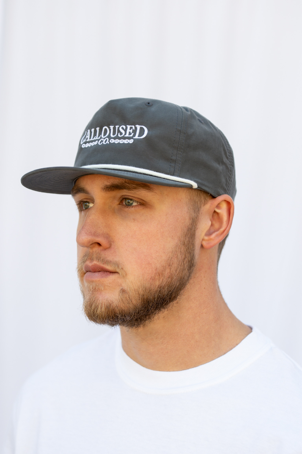Man wearing a gray cap with 'Calloused Co' branding on a white background