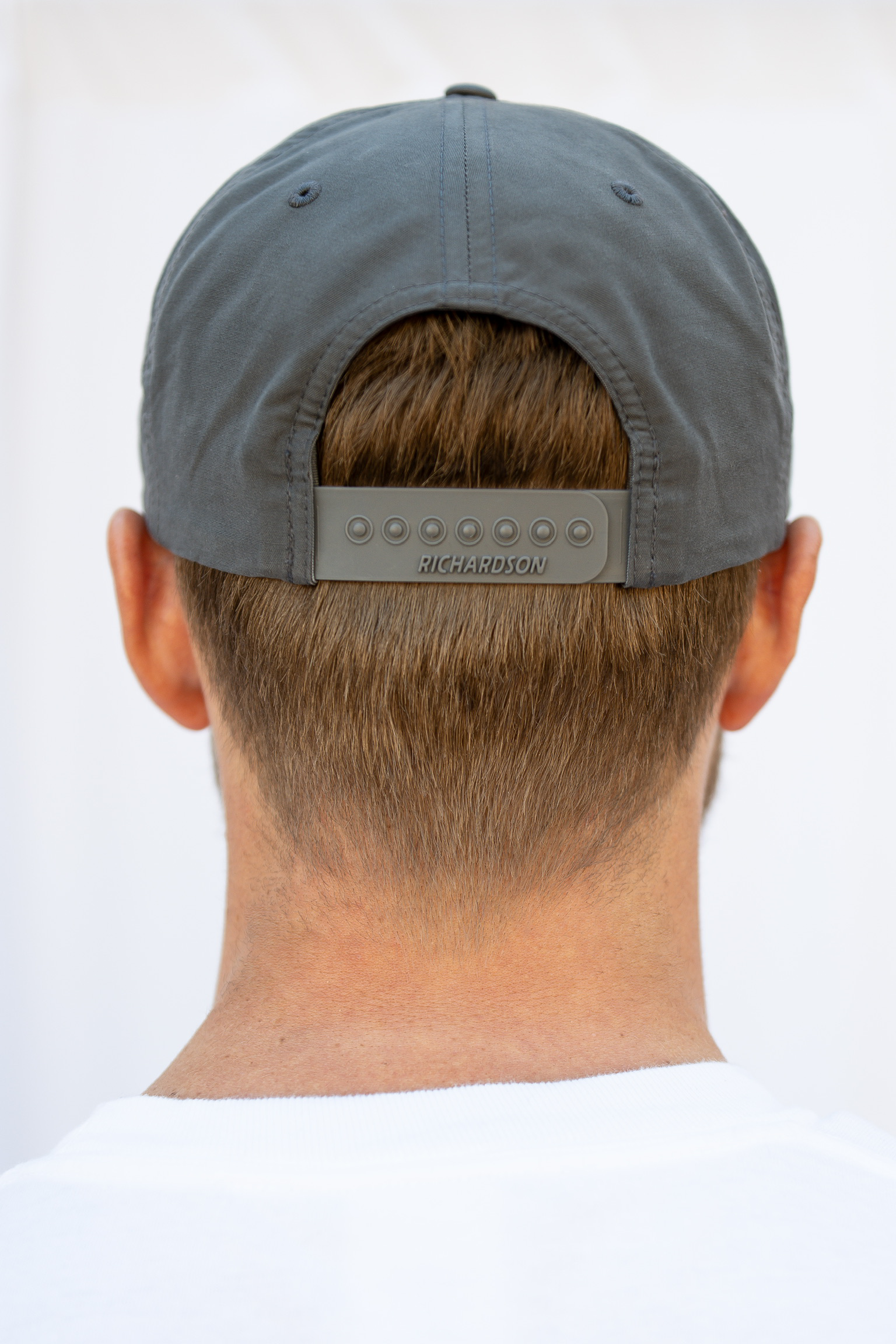 Person wearing a gray cap with a richardson brand logo on the back against a white background