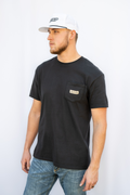 Man wearing a black t-shirt with 'Calloused Co' branding on the pocket and a white cap against a white background