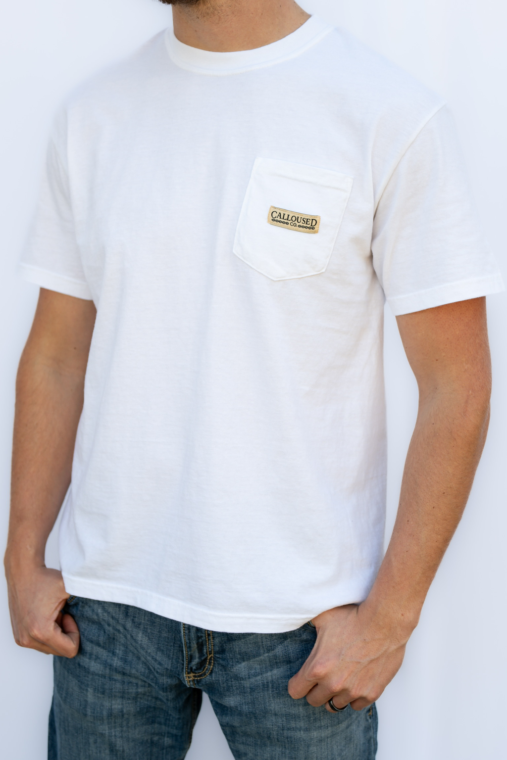 Person wearing a white t-shirt with 'Calloused Co' logo on a plain background