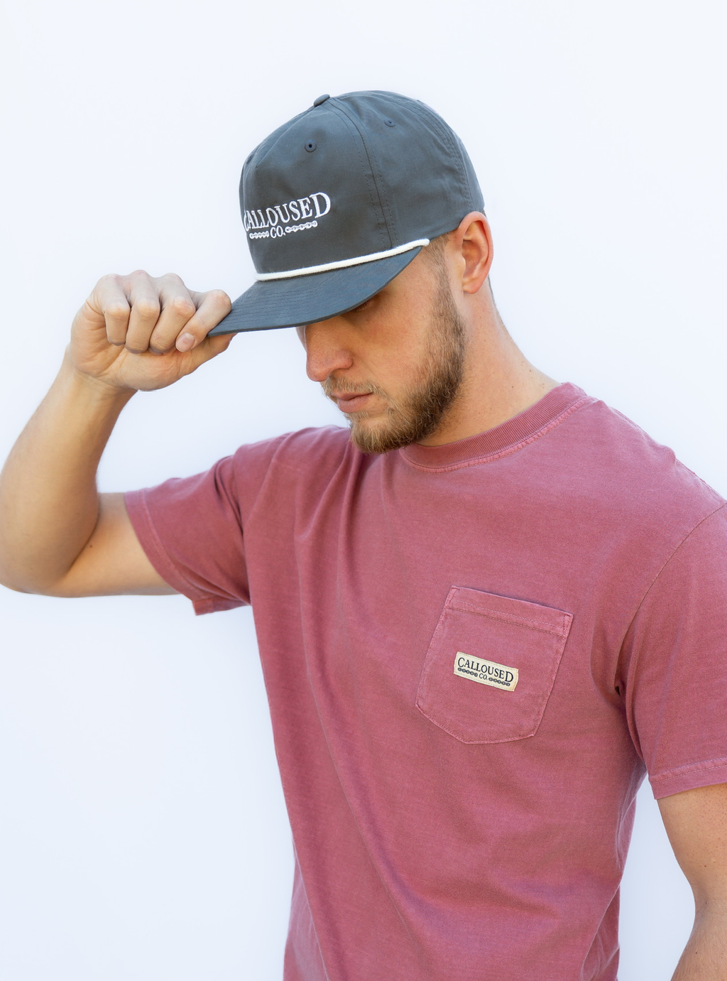 Man wearing a gray cap with 'Calloused Co' branding and a maroon t-shirt with a visible brand logo, against a plain background.