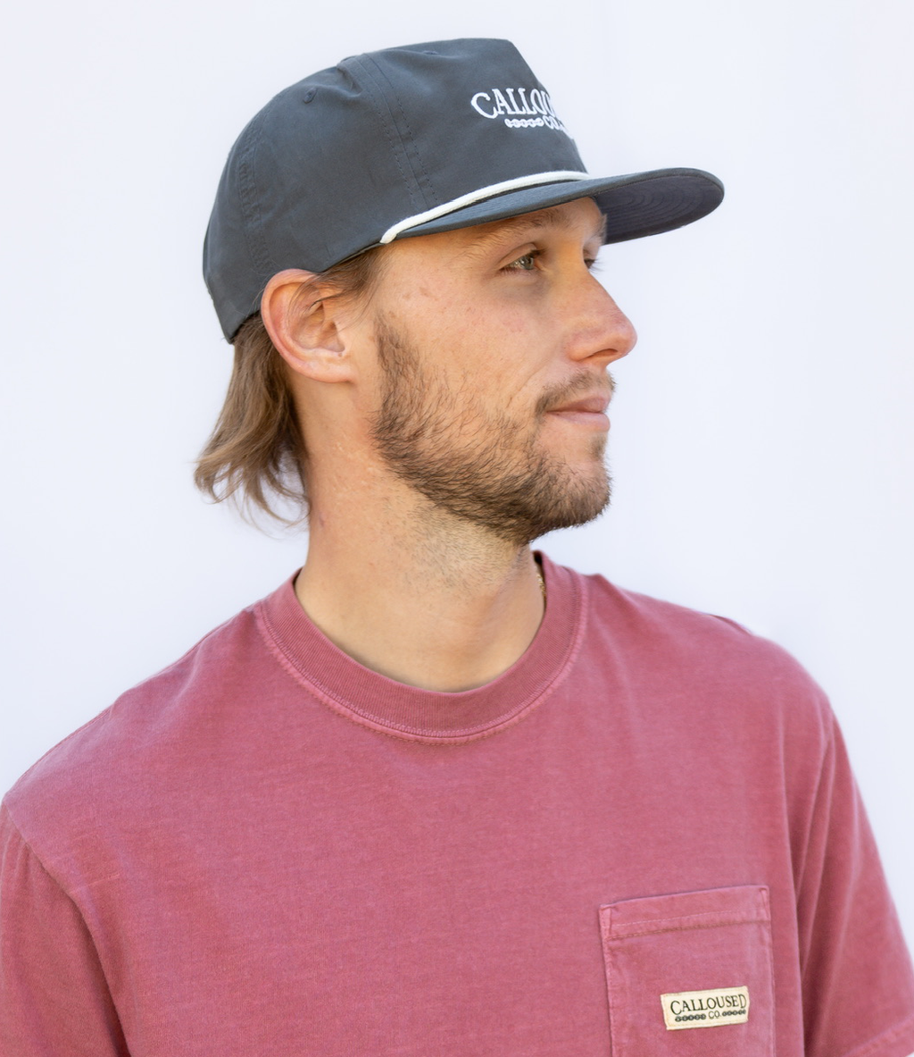Man wearing a dark gray cap with 'Calloused Co' branding and a red shirt.