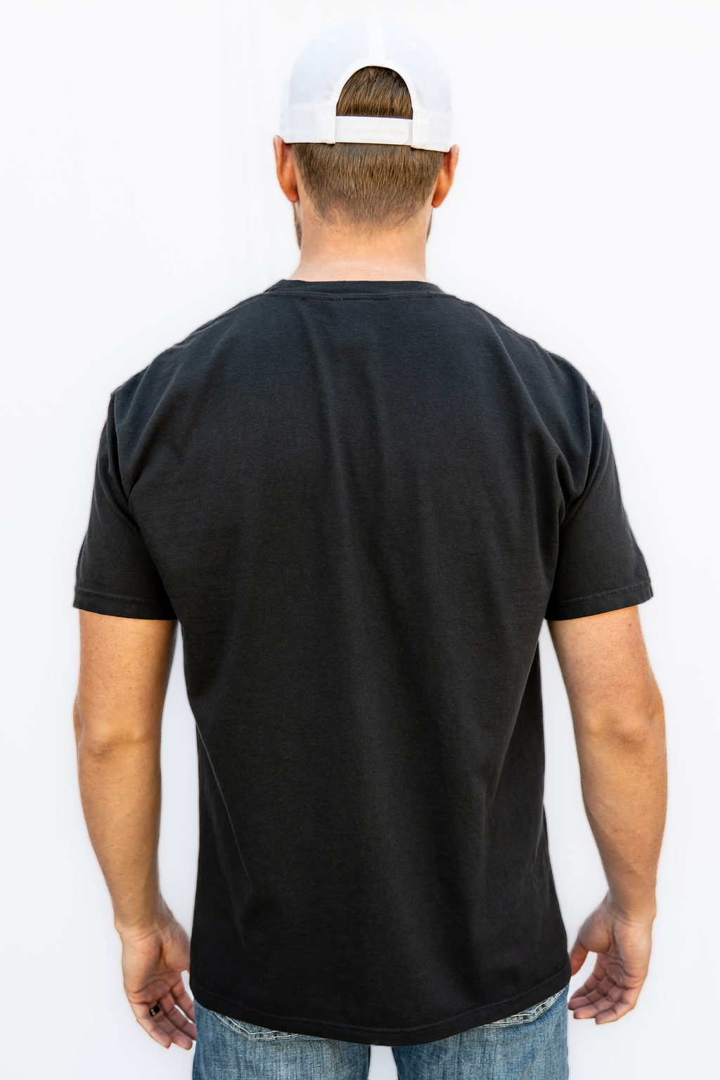 Man wearing a black t-shirt and white cap from behind on a white background