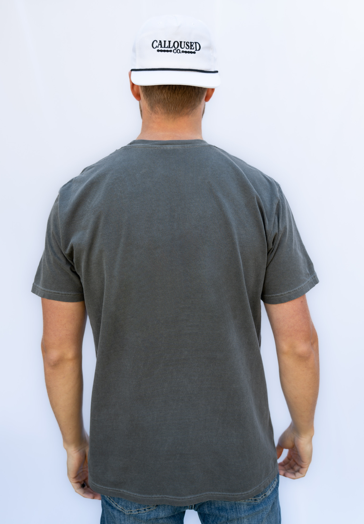 Person wearing a gray t-shirt and white cap with 'Calloused Co' logo on a white background