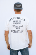 Man wearing a white t-shirt with 'Blue Collar Built to Endure Worn with Pride' text, 'Calloused Co' logo, and a cap on a white background
