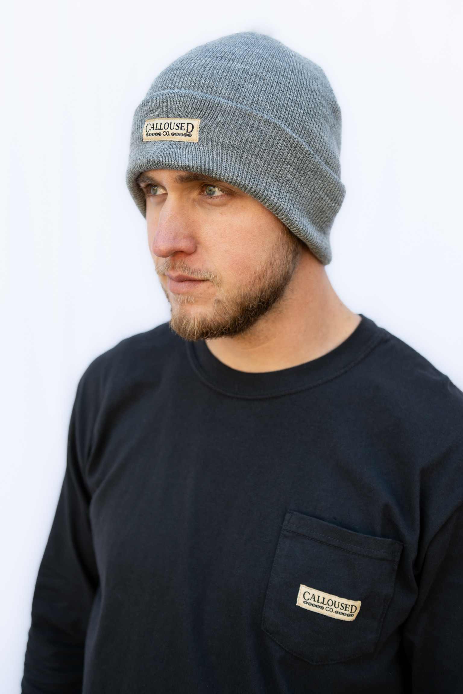 Man wearing a gray beanie and black shirt with 'Calloused Co' logo against a white background