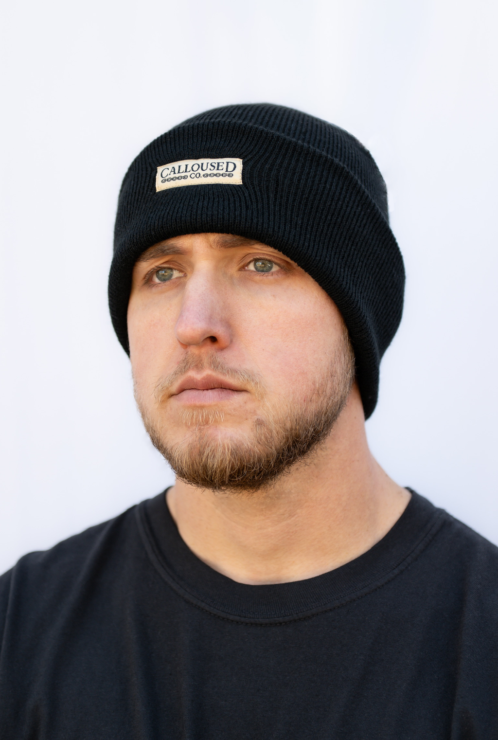 Man wearing a black beanie with 'Calloused Co' brand logo on a white background