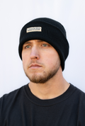 Man wearing a black beanie with 'Calloused Co' brand logo on a white background