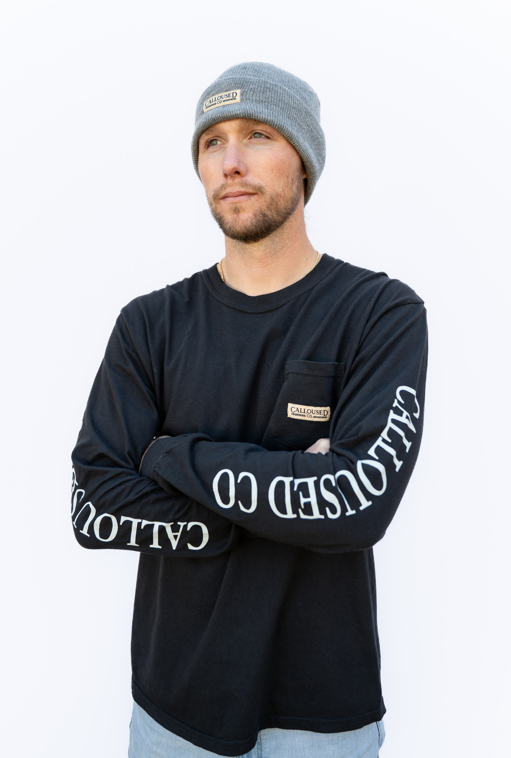 Man wearing a black long-sleeve shirt with 'Calloused Co' branding on sleeves against a white background