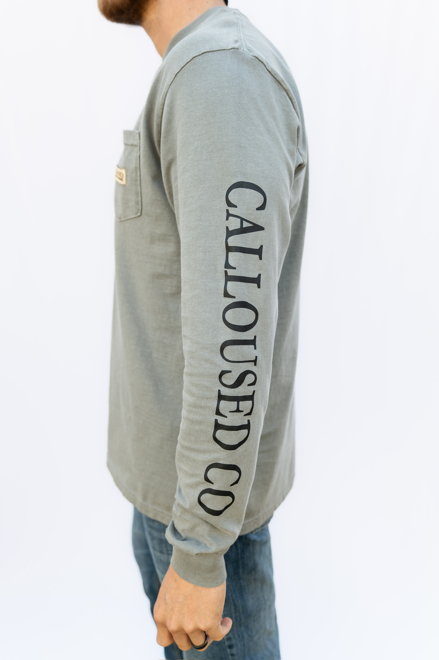 Person wearing a gray long-sleeve shirt with 'Calloused Co' text on sleeve against a white background