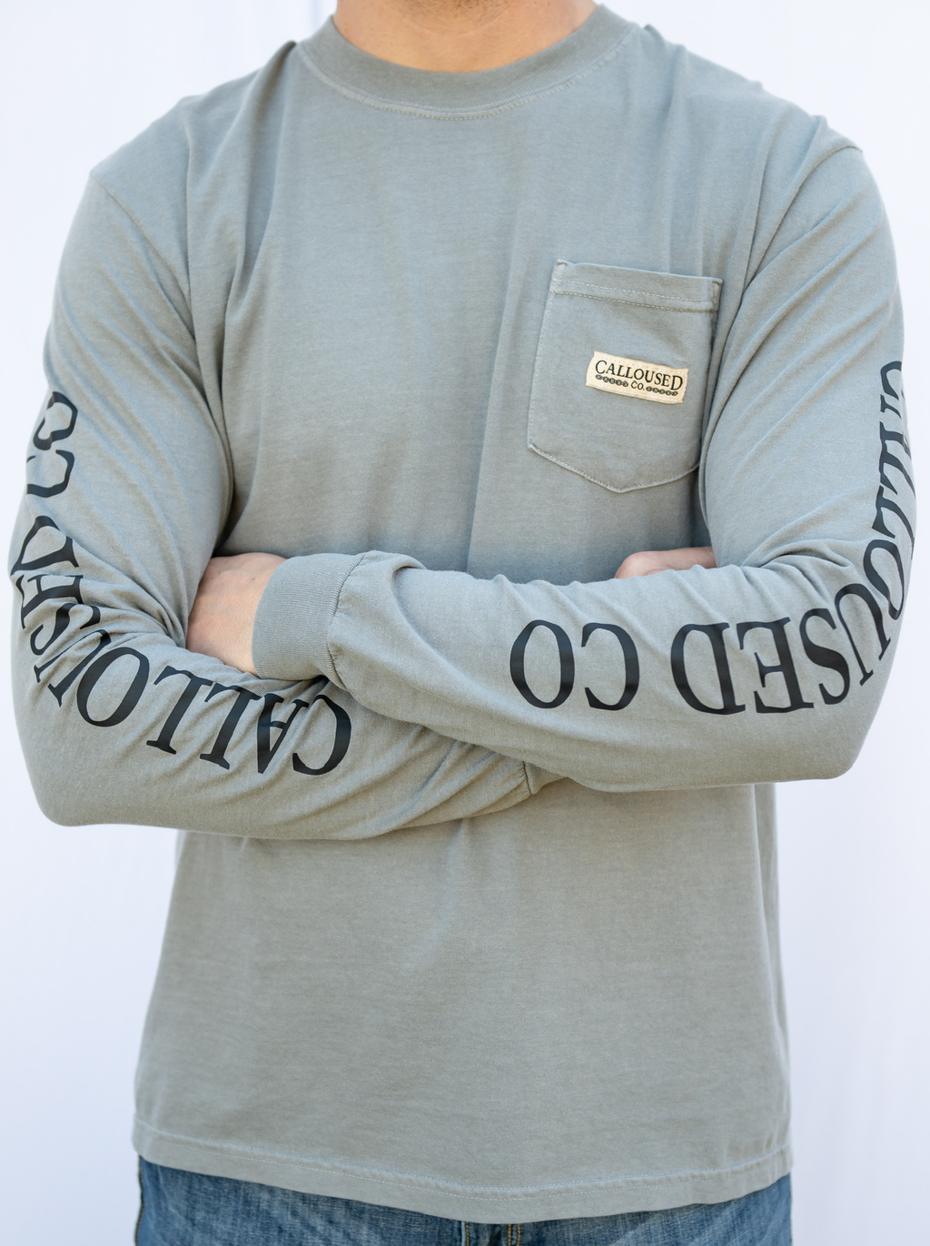 Person wearing a gray long-sleeve shirt with 'Calloused Co.' branding on sleeves and chest pocket.