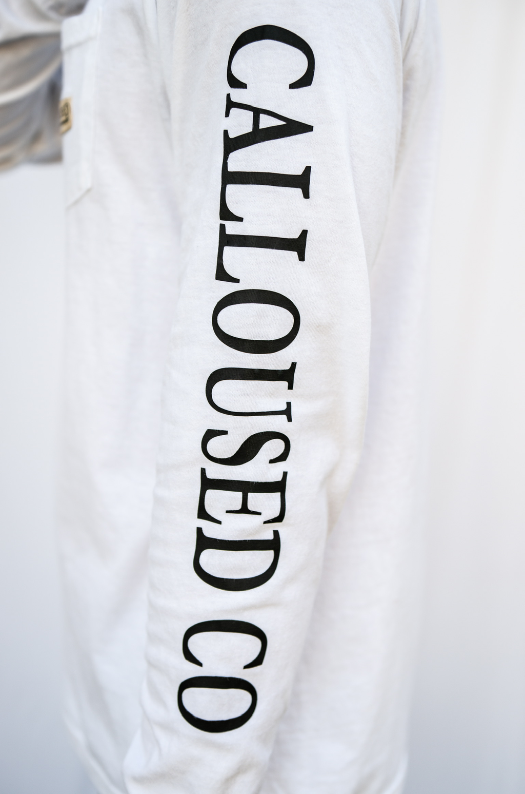 White long sleeve shirt with 'CALLOUSED CO' text on a white background