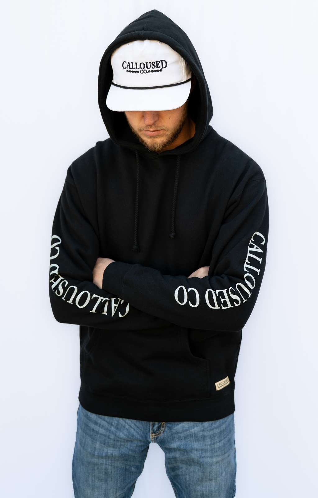 Person wearing a black hoodie with 'CALLOUSED CO' branding on a white background